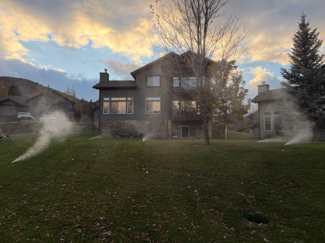 Sprinkler blowout misting across a Park City home's lawn at sunset in October
