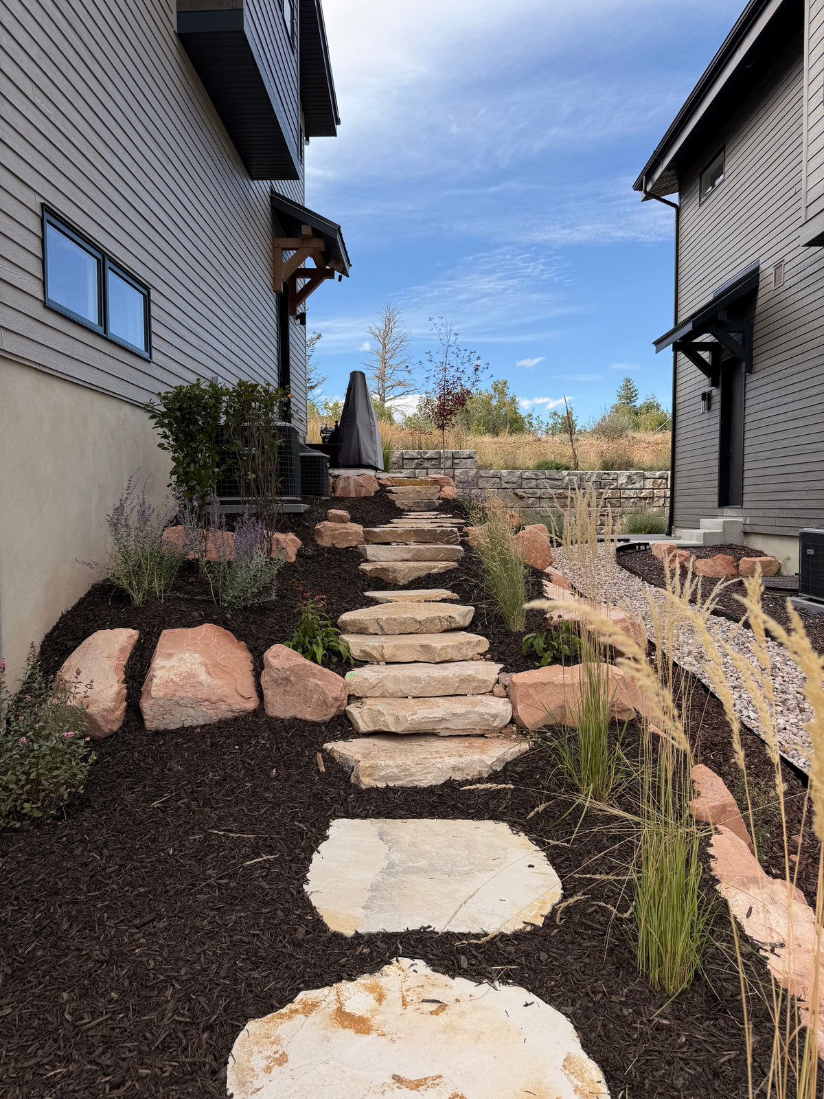 Natural stone stairs with boulders and native plantings in a Park City landscape installation