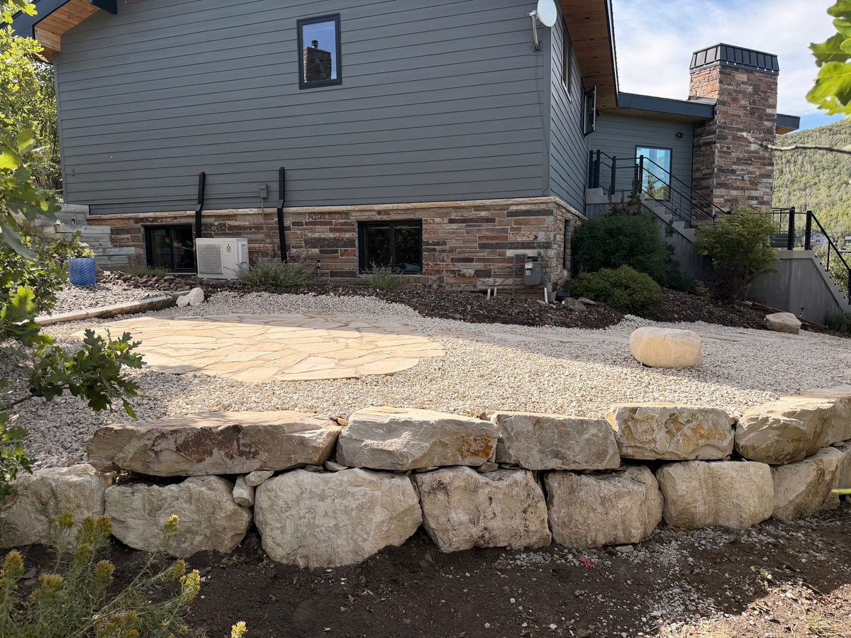 Natural boulder retaining wall with gravel patio in a Park City landscape renovation